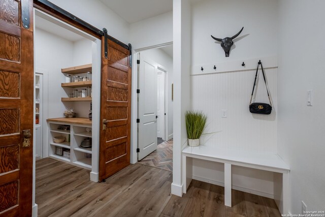 mudroom with a barn door and wood finished floors