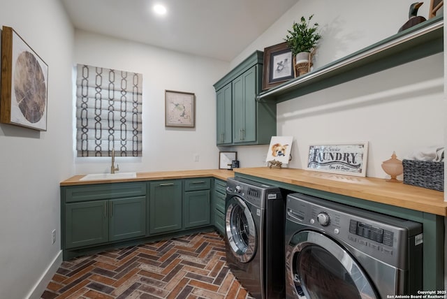 washroom with cabinet space, baseboards, independent washer and dryer, brick floor, and a sink