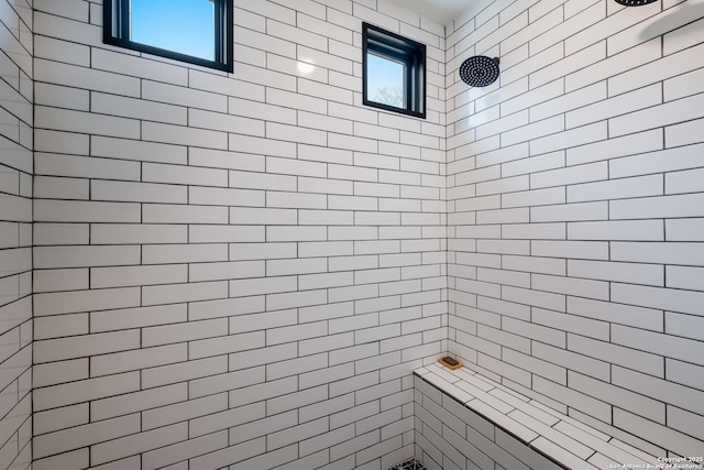 bathroom with a healthy amount of sunlight and tiled shower