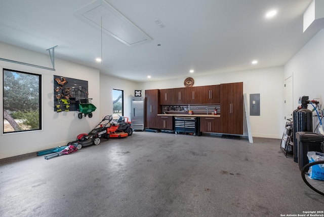 garage with electric panel, baseboards, and recessed lighting