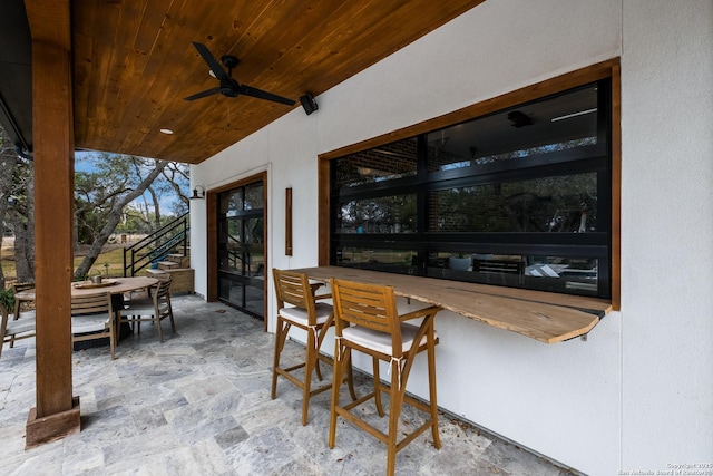 view of patio / terrace featuring exterior bar, outdoor dining area, stairway, and a ceiling fan