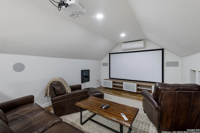 cinema with light wood-type flooring, a wall mounted air conditioner, vaulted ceiling, and baseboards