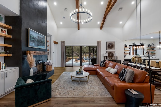 living room featuring an inviting chandelier, high vaulted ceiling, wood finished floors, and a high end fireplace