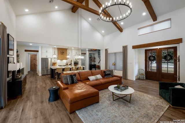 living area featuring french doors, a chandelier, light wood-style flooring, high vaulted ceiling, and beamed ceiling