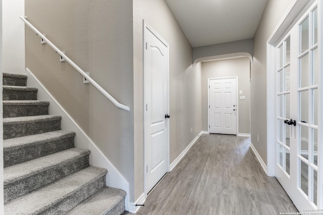 foyer entrance featuring arched walkways, wood finished floors, stairs, and baseboards