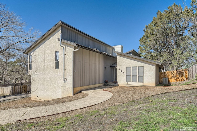 rear view of house featuring stucco siding, fence, and central AC unit