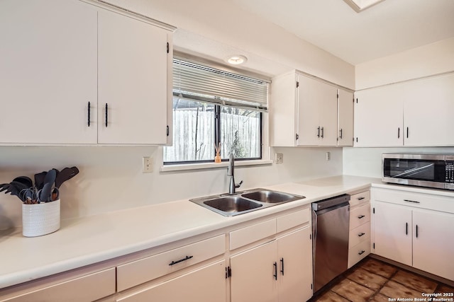 kitchen featuring white cabinets, appliances with stainless steel finishes, light countertops, and a sink