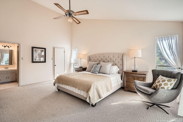 bedroom with light colored carpet, a ceiling fan, connected bathroom, a sink, and high vaulted ceiling