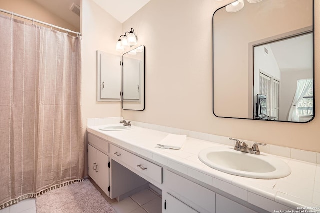 bathroom with lofted ceiling, double vanity, a sink, and tile patterned floors