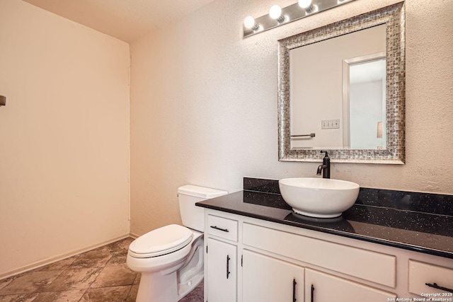 bathroom featuring toilet, vanity, and baseboards