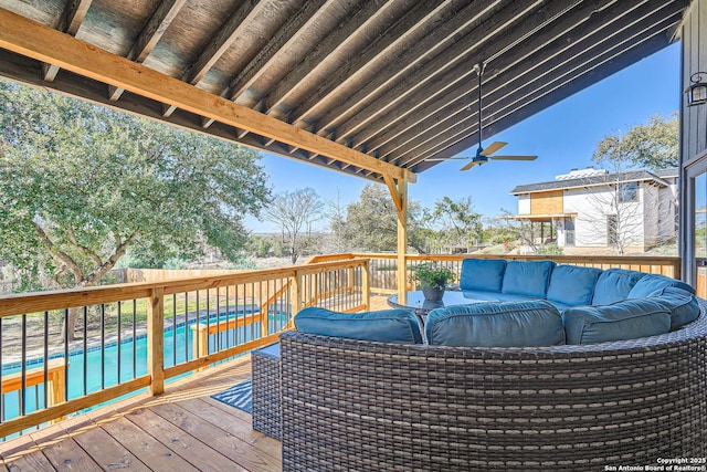 wooden terrace featuring a ceiling fan, fence, a swimming pool, and an outdoor hangout area