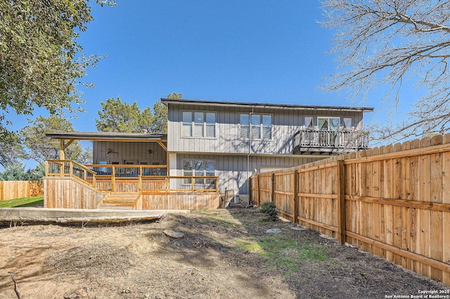 rear view of house with fence and a deck