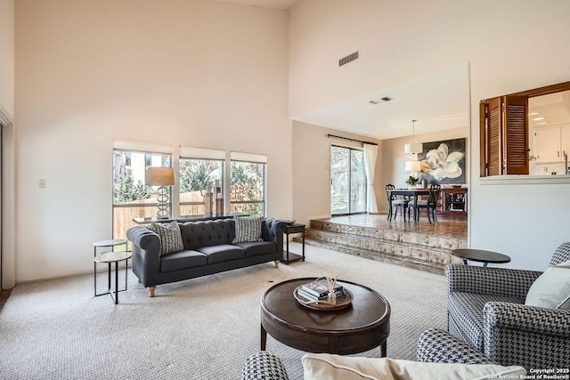 carpeted living area with visible vents and a high ceiling