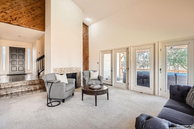 carpeted living room featuring high vaulted ceiling, a fireplace, and stairway