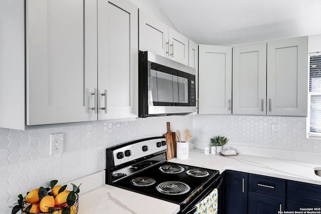 kitchen featuring blue cabinets, white cabinets, electric stove, light stone countertops, and stainless steel microwave