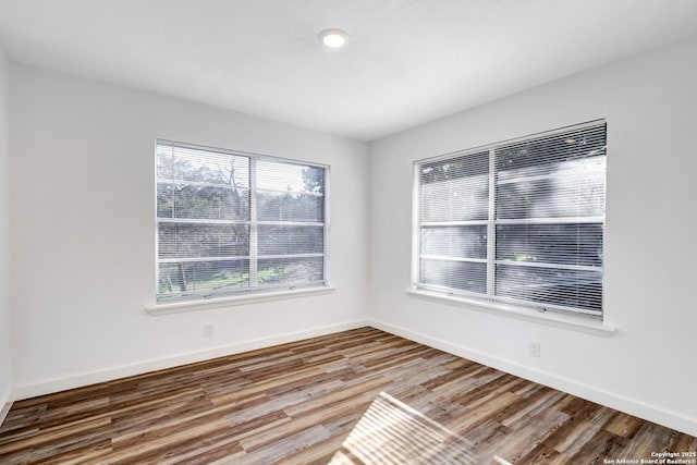 spare room featuring baseboards and wood finished floors