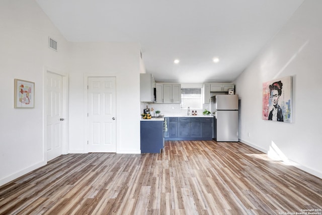 kitchen with visible vents, light countertops, light wood-type flooring, gray cabinets, and freestanding refrigerator