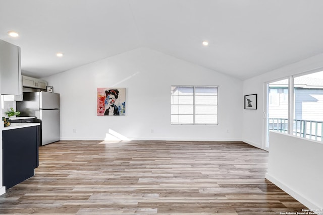 kitchen featuring plenty of natural light, freestanding refrigerator, light countertops, and vaulted ceiling