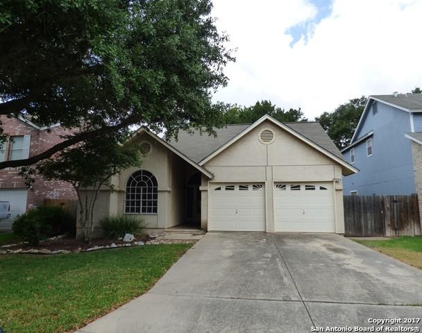 ranch-style house featuring driveway, an attached garage, fence, and stucco siding