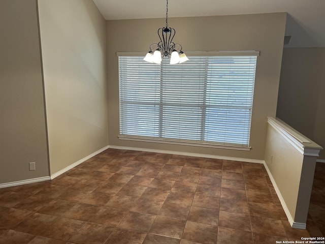 spare room featuring baseboards and a notable chandelier