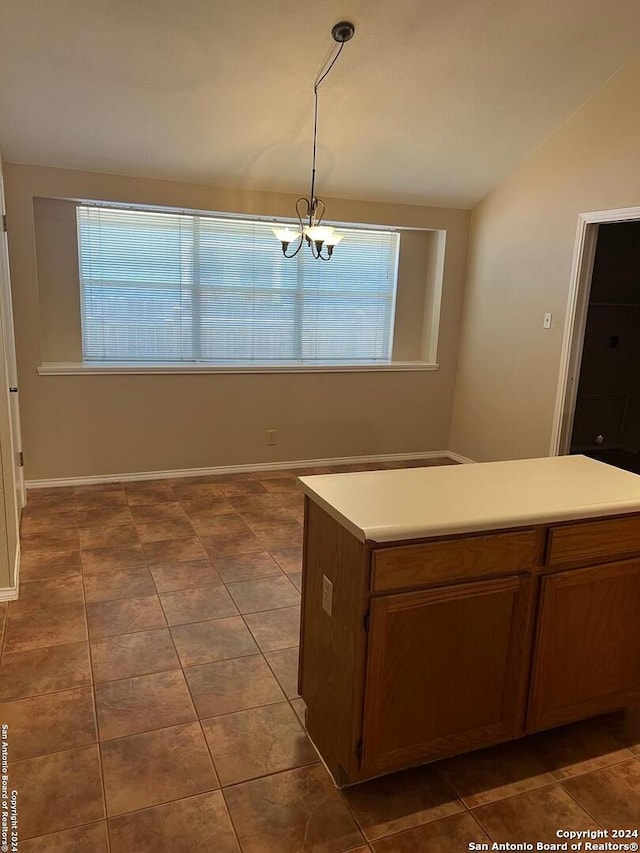 unfurnished dining area featuring baseboards, a chandelier, vaulted ceiling, and dark tile patterned flooring