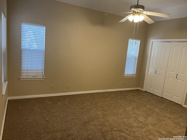 unfurnished bedroom featuring carpet, a closet, multiple windows, and baseboards