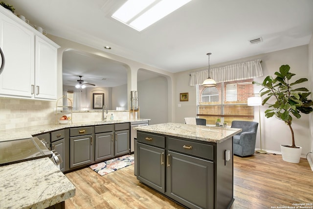 kitchen with arched walkways, gray cabinets, white cabinetry, and a center island