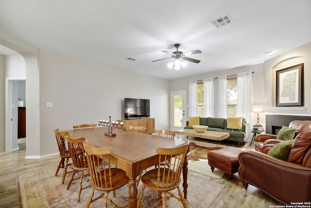 dining space featuring a ceiling fan, arched walkways, visible vents, and light wood-style flooring