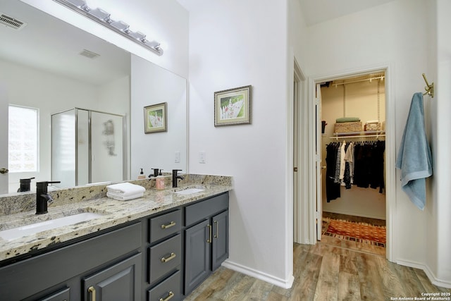 full bathroom featuring a stall shower, visible vents, a walk in closet, and a sink