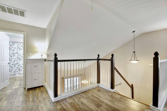 hallway featuring visible vents, light wood-style flooring, and an upstairs landing