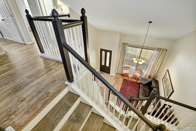 staircase featuring a notable chandelier, baseboards, and wood finished floors