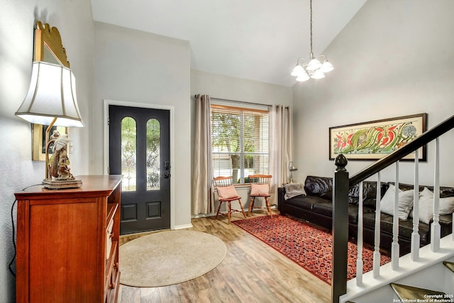 entrance foyer featuring high vaulted ceiling, light wood-style flooring, stairs, and a chandelier