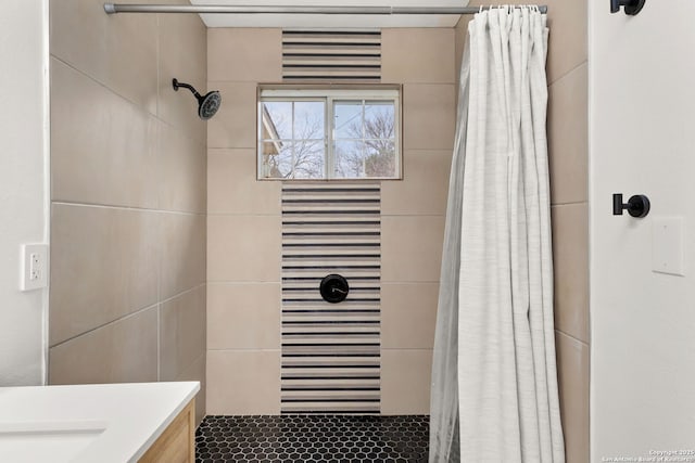 bathroom with a tile shower and vanity