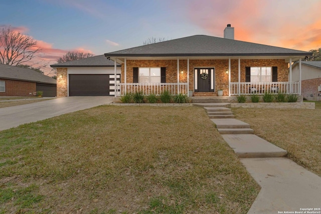 view of front of property with brick siding, a yard, a porch, an attached garage, and driveway