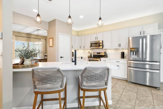 kitchen featuring white cabinets, light countertops, appliances with stainless steel finishes, tasteful backsplash, and decorative light fixtures