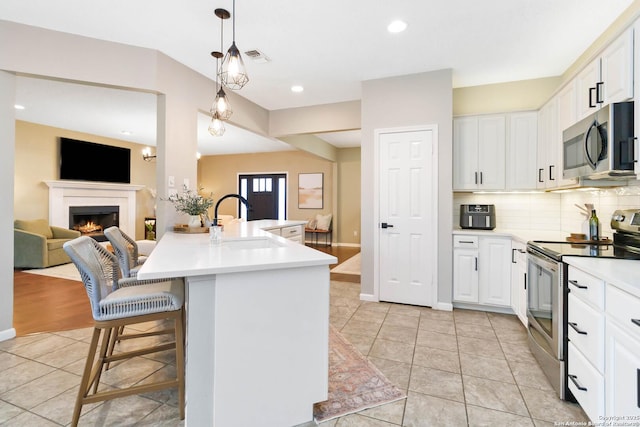 kitchen featuring open floor plan, light countertops, appliances with stainless steel finishes, and a sink