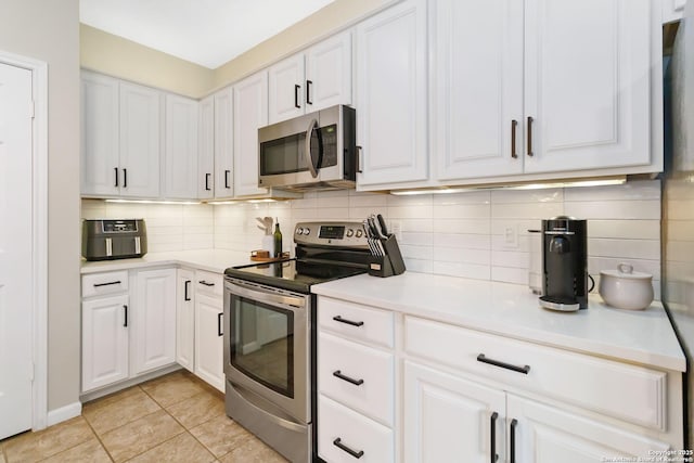 kitchen featuring light tile patterned floors, decorative backsplash, appliances with stainless steel finishes, light countertops, and white cabinetry