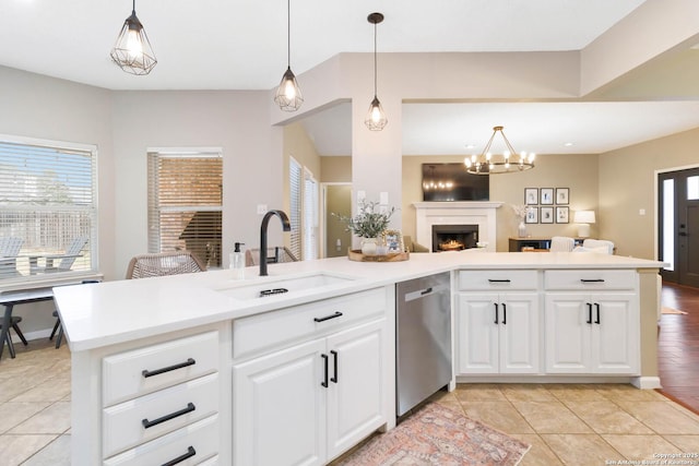 kitchen with open floor plan, a sink, light countertops, pendant lighting, and stainless steel dishwasher