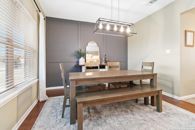 dining space with dark wood-style floors, visible vents, and baseboards