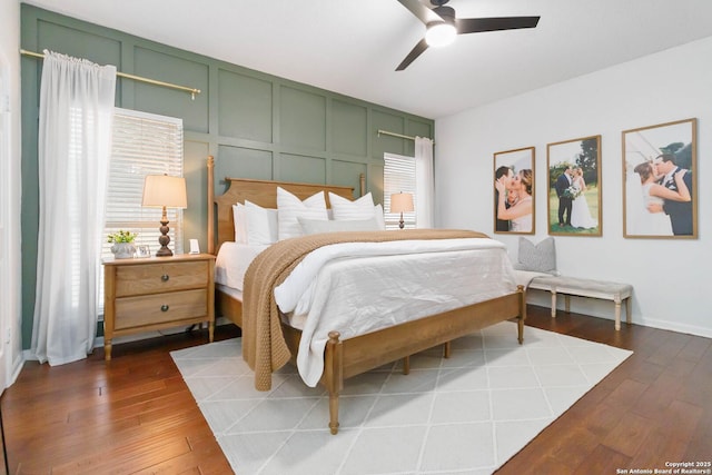 bedroom featuring ceiling fan, dark wood-type flooring, baseboards, and a decorative wall