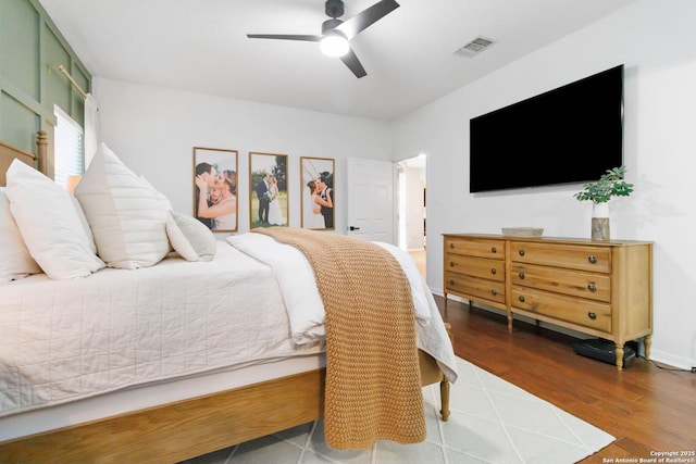 bedroom with ceiling fan, wood finished floors, visible vents, and baseboards