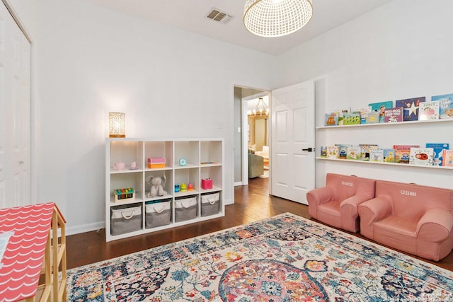 game room featuring dark wood-style floors, visible vents, baseboards, and an inviting chandelier