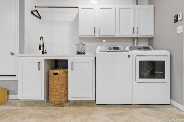 laundry room with baseboards, cabinet space, a sink, and washing machine and clothes dryer