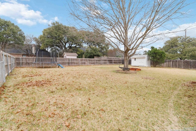 view of yard with a trampoline, an outbuilding, a fenced backyard, and a shed