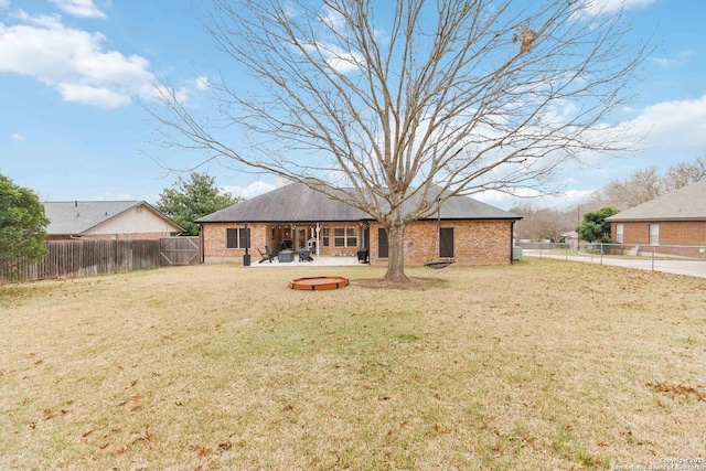 rear view of property featuring brick siding, a lawn, and a fenced backyard