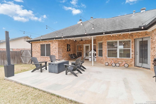 rear view of property featuring an outdoor fire pit, a shingled roof, a patio, fence, and brick siding