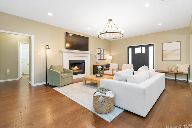 living room with a lit fireplace, baseboards, wood finished floors, and recessed lighting