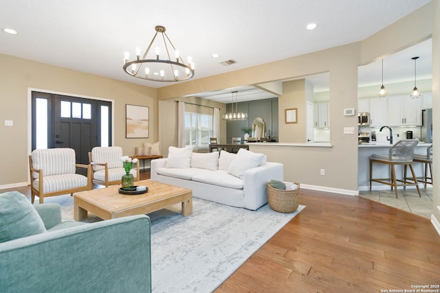 living area featuring recessed lighting, visible vents, baseboards, light wood-type flooring, and an inviting chandelier