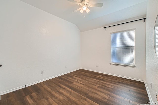 unfurnished room featuring lofted ceiling, dark wood-style floors, baseboards, and a ceiling fan