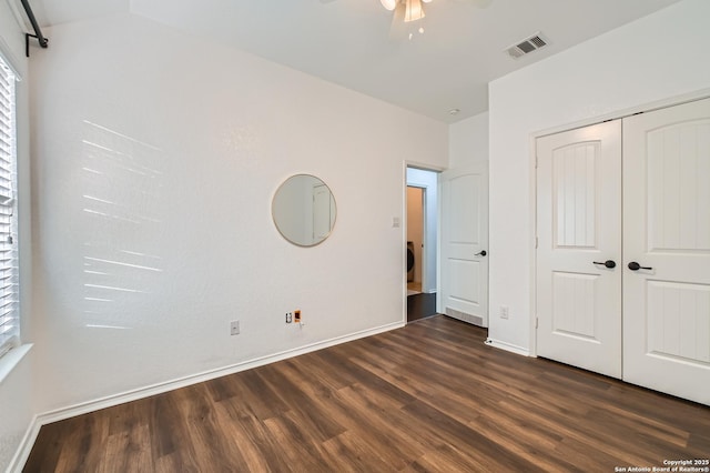 unfurnished bedroom with baseboards, a closet, visible vents, and dark wood-type flooring